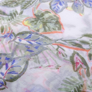 Detail of thin mesh fabric with colorful green and pink leaf patterns and fringe tassels