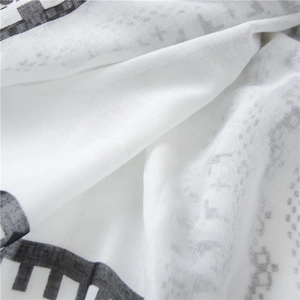 Macro detail of breathable cotton linen scarf with black geometric prints on white fabric