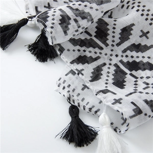 Detailed macro view of black geometric patterns and fine fringe on a white cotton scarf
