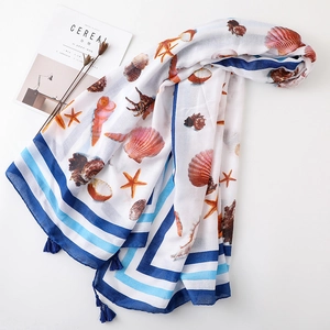 Detail of seashell and starfish print on linen scarf with blue tassel edge