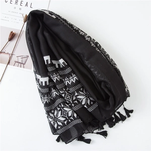 Detail of black cotton scarf with white geometric patterns and fringe edges on white desk