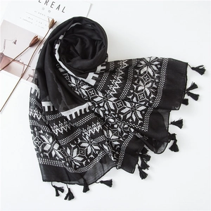 Close-up of black and white geometric scarf with fringe and snowflake patterns