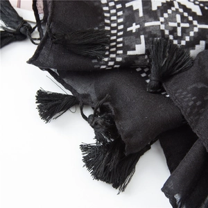 Macro detail of black cotton linen scarf with white geometric print and fringe edges