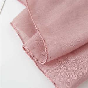Detail der hochwertigen Overlock-Naht an einem hellrosa Baumwoll-Leinen-Schal