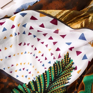 Détail d'une écharpe en coton et lin avec motifs géométriques et plumes colorés