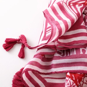 Detailed macro shot of red and white floral print scarf with soft woven tassels
