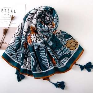 Detail of floral printed cotton linen shawl with stylish turquoise tassels and fringe