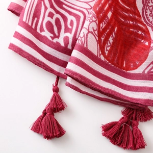 Detail of red floral cotton scarf showing intricate bohemian pattern and tassel fringe