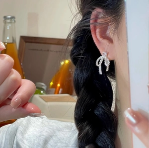 Elegant silver bow earrings with heart-shaped zircon shown on a model in a refined style