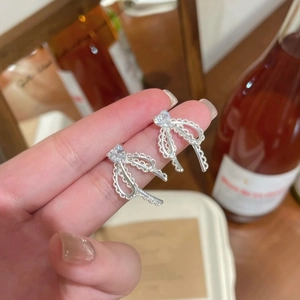 Silver bow stud earrings with heart shaped cubic zirconia stone in a lifestyle setting