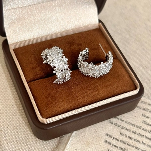 Elegant silver C-shaped pavé earrings with cubic zirconia in a vintage jewelry box