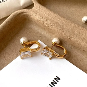 Close-up of geometric square zircon and pearl earrings with golden U-shaped hooks
