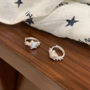 Minimalist silver star earrings with zircons on dark wooden table and fabric
