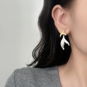Elegant gold and silver contrast fishtail earrings with brushed texture on model