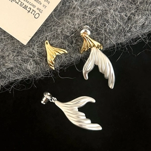 Macro detail of bicolored fishtail earrings with metallic texture and elegant design