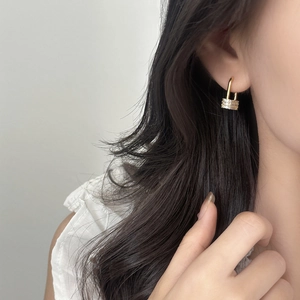 Elegant gold-plated padlock earrings with micro-set zircons worn by a model