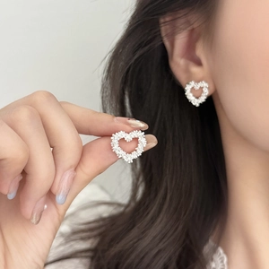 Elegant silver heart stud earrings with sparkling crushed silver texture on model's ear
