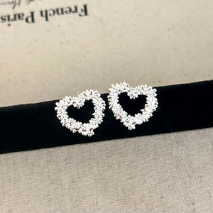 Textured silver heart stud earrings with granular finish on black velvet display base