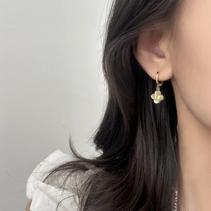 Elegant gold clover earrings with cat eye stone and zircon on a female model