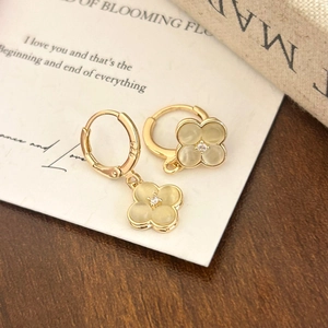 Macro shot of gold four-leaf clover earrings with cat-eye stones and 925 silver stamp