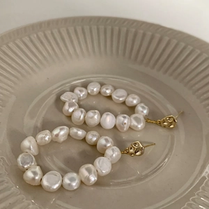Macro detail of baroque freshwater pearl earrings on a textured ceramic tray