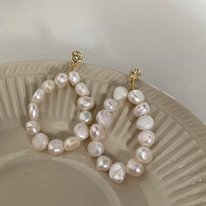 Close-up of Baroque freshwater pearl hoop earrings with textured gold plating finish