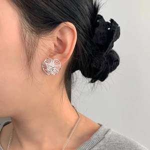 Silver hollow flower stud earrings with pleated radiating texture on female model