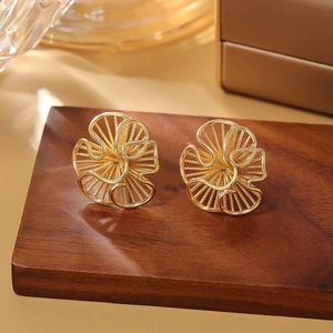 Macro shot of gold hollow flower earrings on a wooden stand with elegant glass accents