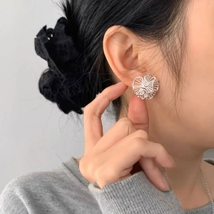 Elegant hollow floral stud earring in silver finish shown on model with natural lighting