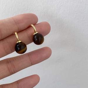 Detail of tiger eye stone earrings held in hand to demonstrate the actual product size