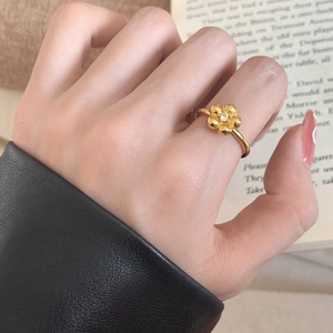 Elegant gold flower ring featuring a sparkling central zircon, worn against a classic background