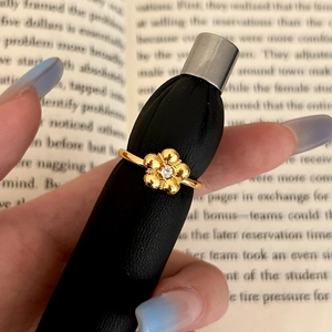 Macro detail of gold flower ring with sparkling zircon center and textured petals