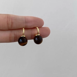 Tiger eye stone earrings with golden loops held in hand against a neutral background