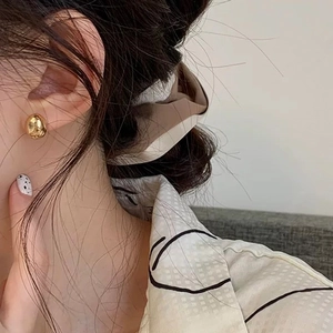 Elegant gold pebble earrings with a minimalist irregular design shown on a female model