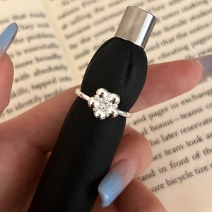 Macro shot of silver flower ring with zircon stone on a sleek black jewelry display stand