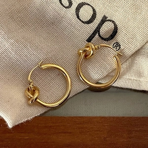 Minimalist gold knot hoop earrings featuring a polished finish and a secure snap closure