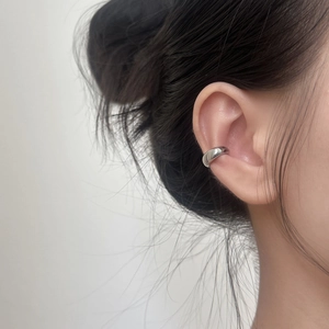Sleek silver C-shaped ear cuff on ear, minimalist clip-on jewelry with polished finish