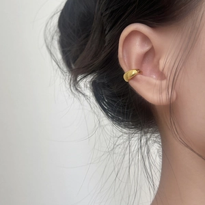 Minimalist gold-plated C-shaped ear cuff with a polished finish worn on the ear