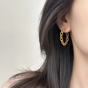 Fashionable gold interlocking chain link hoop earrings worn by a model in close-up view