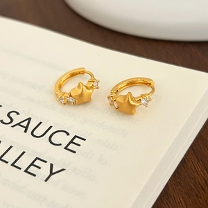 Detail of star-shaped 18K gold hoop earrings with matte finish and inset cubic zirconia