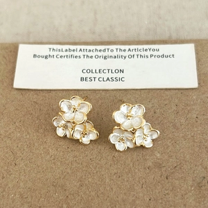 Boucles d'oreilles clous trois fleurs blanches et base dorée sur carte cadeau