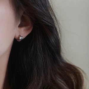 Elegant silver minimalist double-loop huggie earrings worn by model for fashion style
