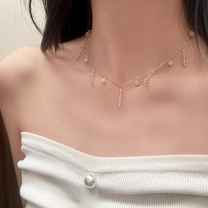 Collier élégant en or avec perles roses et glands en cristal sur la clavicule