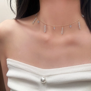 Collier élégant en or avec glands en pierre naturelle bleue sur le cou d'un modèle