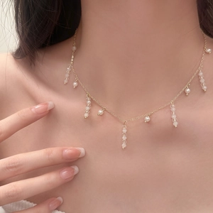 Collier à pampilles doré élégant avec perles blanches et cristaux porté par un mannequin