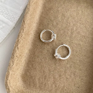 Vue macro des boucles d'oreilles nœud en argent sur fond brun avec détails métalliques