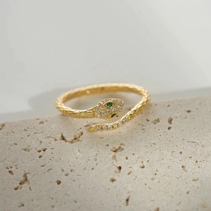 Macro detail of golden snake ring featuring green gem eyes and sparkling pavé crystals