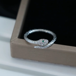 Close-up of silver snake ring with sparkling crystals and green gem eyes on jewelry box