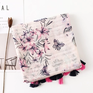 Detail of pink cotton-linen scarf with floral butterfly prints and long colorful tassels