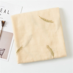 Detailstruktur eines Baumwoll-Leinen-Schals mit goldener Federstickerei auf Beige